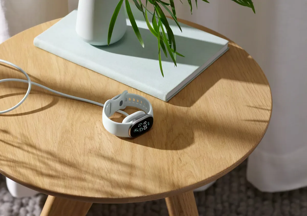 Fitbit Edge manyetik şarj kablosuyla sehpanın üzerinde şarj olurken