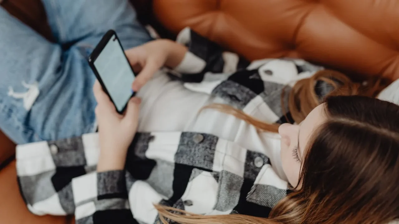 Sosyal medyada e-Devlet ile yaş doğrulama 1 Kasım’da başlıyor, işte yeni kurallar Kanepede uzanarak akıllı telefonunu kullanan genç bir kız