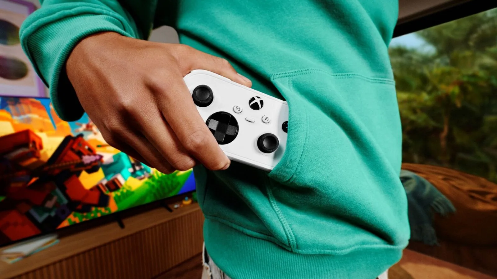 Beyaz Xbox Nano Controller'ı sweatshirt cebine koyan bir kişi